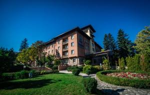 a building with a garden in front of it at Spa Hotel Dvoretsa in Velingrad