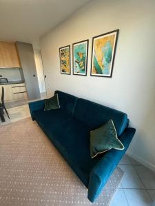 un divano blu in soggiorno con dipinti alle pareti di Apartament Bielik a Międzyzdroje
