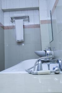 um lavatório de casa de banho com uma torneira e um espelho em Steric Hotel Kampala em Kampala