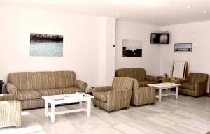 sala de estar con sofás, mesas y TV en Apartamentos Arcos Playa, en S'Illot