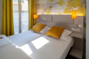 a bedroom with two beds with yellow pillows at Hotel Victoria in Strasbourg