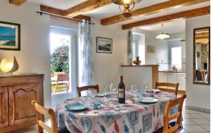 a dining room with a table with a bottle of wine at Maison sur jardin clos au calme à la campagne et proche des plages in Mahalon +9 photos