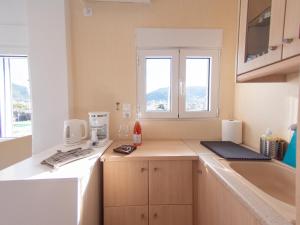 a kitchen with a counter and a sink and windows at Lux Sea Studio - Porto Rafti in Porto Rafti