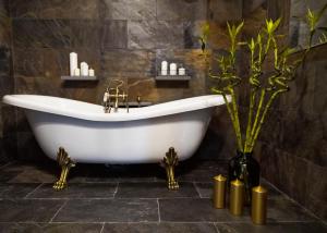 Hotel Do Poduchy في زافيارتشي: حوض استحمام في الحمام مع الشموع والنباتات