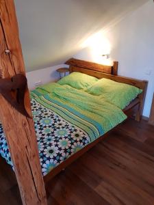 a wooden bed with a green comforter in a room at Apartmán Sýkorka in Hartmanice