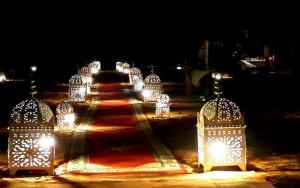 un camino iluminado con luces encendidas por la noche en Chigaga Luxury Camp en Mhamid