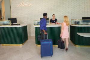 a man and a woman standing at a counter with luggage at Leonardo Hotel Bristol City in Bristol