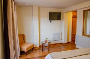 a room with a bed and a chair and a television at Eco-Hotel Pension Alemana in Cusco