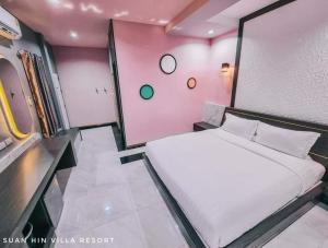 a small bedroom with a white bed and pink walls at สวนหินวิลล่า รีสอร์ท in Ban Chot