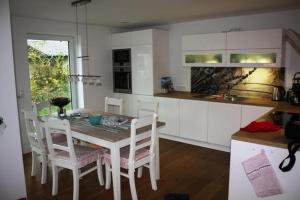 une cuisine avec une table et des chaises et une cuisine avec des placards blancs dans l'établissement Ferienhaus Bullerbü, à Bedekaspel