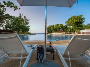 two chairs and an umbrella on a beach at Trident Hotel in Port Antonio