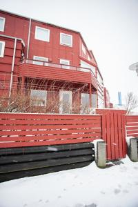 a red building with a bench in the snow at Cozy / Nordic House / Baker / Svartifossur in Tórshavn