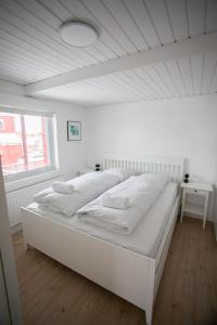 Cama blanca grande en habitación blanca con ventana en Cozy / Nordic House / Baker / Svartifossur, en Tórshavn