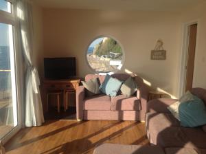a living room with a pink couch and a window at PORTHOLES in Ventnor