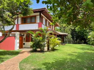 uma casa com um relvado verde em frente em Duplex aconchegante Cond Reserva Praia do Forte em Mata de São João