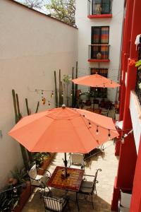 zwei orangefarbene Sonnenschirme auf einer Terrasse mit Tischen und Stühlen in der Unterkunft Posada Don Mario in Oaxaca de Juárez
