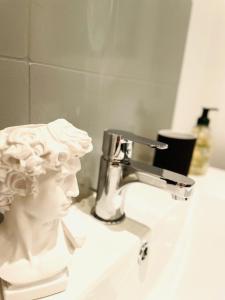a bathroom sink with a statue of a head on it at La Suite Beauvaisienne, T2 hyper centre in Beauvais