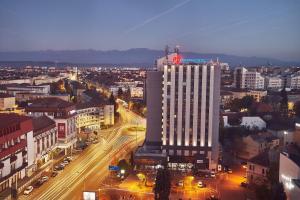 a tall white building with a flag on top of it at MyContinental Sibiu in Sibiu