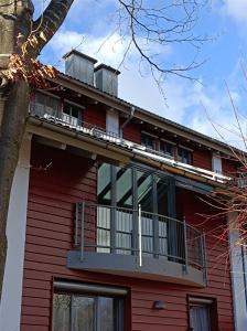 une maison rouge avec un balcon et un arbre dans l'établissement Galeria Helmut, à Peiting