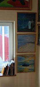 un mur avec quatre peintures, une fenêtre et des livres dans l'établissement Galeria Helmut, à Peiting