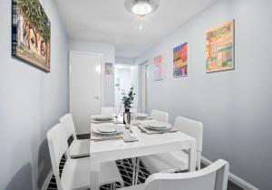 uma sala de jantar branca com uma mesa e cadeiras brancas em Hampton Hideaway By My Getaways em Brighton & Hove