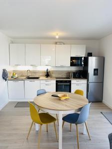 eine Küche mit einem Holztisch und Stühlen in der Unterkunft Hemisphere, Appartement neuf avec ascenseur proche de Carnac Centre in Carnac