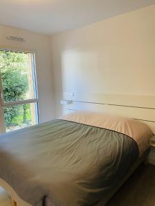 Bett in einem weißen Zimmer mit Fenster in der Unterkunft Hemisphere, Appartement neuf avec ascenseur proche de Carnac Centre in Carnac