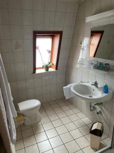 a bathroom with a sink and a toilet and a window at Gasthaus Neue Mühle in Westhausen