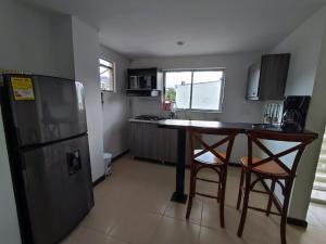 a small kitchen with a refrigerator and two bar stools at Buena Vista Suites in Armenia
