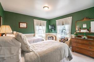 a green bedroom with two beds and a mirror at Abacot Hall Bed & Breakfast in Niagara on the Lake