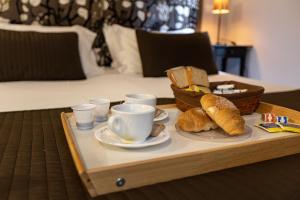 a tray with bread and cups and a tray of coffee and pastries at San Lorenzo Rooms in Rome