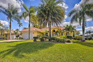 a yellow house with palm trees in a yard at Waterfront Pool and Spa Relaxing Cape Coral Retreat in Cape Coral