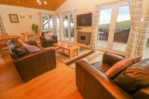 a living room with leather furniture and a large window at Lodge 23 in Torpoint