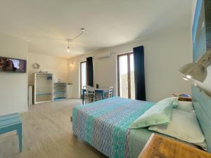 a bedroom with a bed and a table and a kitchen at Dery Alghero Holiday Rooms in Alghero