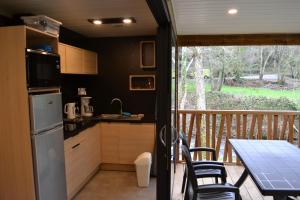 cocina con mesa y sillas y balcón en Chalets au bord de l'eau, en Caudebronde