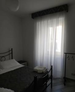 a bedroom with a bed and a window with white curtains at Casa Vacanza Diana in Agnone