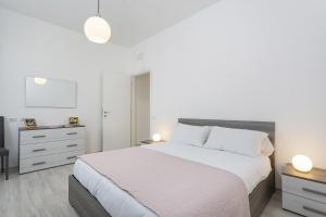- une chambre blanche avec un grand lit et une commode dans l'établissement Contemporary apartment in Sturla by Wonderful Italy, à Gênes