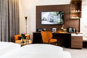 Hotel Am Schloss Aurich - Schlossresidenz في أوريتش: غرفة في الفندق بها سرير وتلفزيون على الحائط