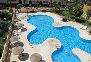 uma vista sobre uma grande piscina com guarda-sóis em Fabulous sunny apartment em Almerimar