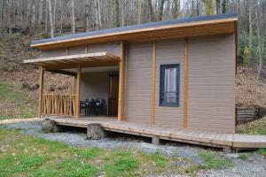 a small cabin with a deck in the woods at Chalets au bord de l'eau in Caudebronde