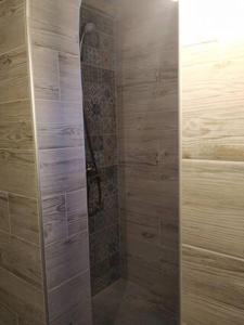 a bathroom with a shower with wooden walls at ORFEAS HOUSE 2 in Patitiri