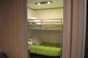 a room with two bunk beds with a green ottoman at Chalets au bord de l'eau in Caudebronde