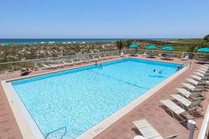 a swimming pool with chairs and the ocean in the background at Navarre Beach Regency 308 in Navarre