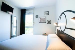 a bedroom with a white bed and a window at Kyriad Nuits-Saint-Georges in Nuits-Saint-Georges