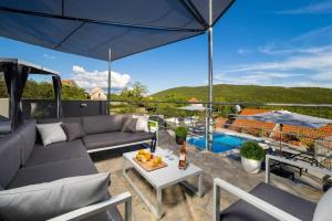 a patio with a couch and an umbrella and a pool at Villa Vito - with heated pool, whirlpool, gym in Šarići