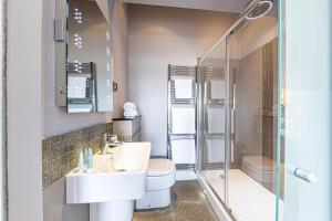 a bathroom with a sink and a toilet and a shower at Escape Boutique B&B in Llandudno