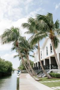 a white building with palm trees next to a river at The Capitana Key West in Key West