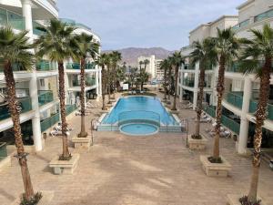 a swimming pool in the middle of a building with palm trees at בוטיק לה פלמורה אילת in Eilat