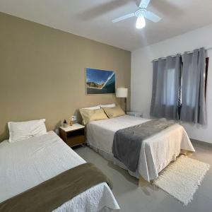 a bedroom with two beds and a ceiling fan at Pousada Reserva de Itaúna in Saquarema