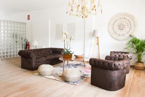 una sala de estar con muebles de cuero marrón y una lámpara de araña. en Villaprado, en Cambados